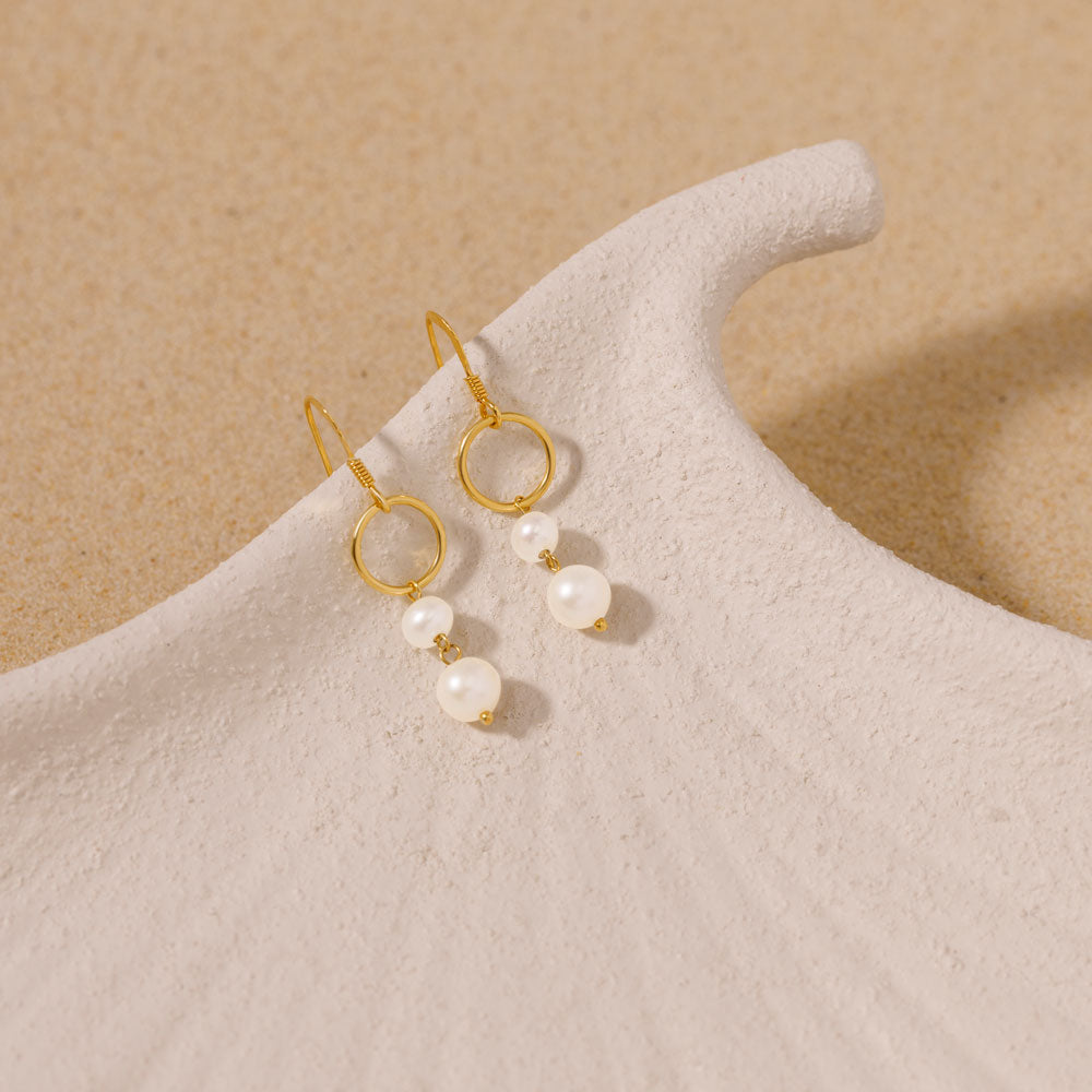 Gold-plated dangle earrings adorned with lustrous pearls, showcasing elegance and style.