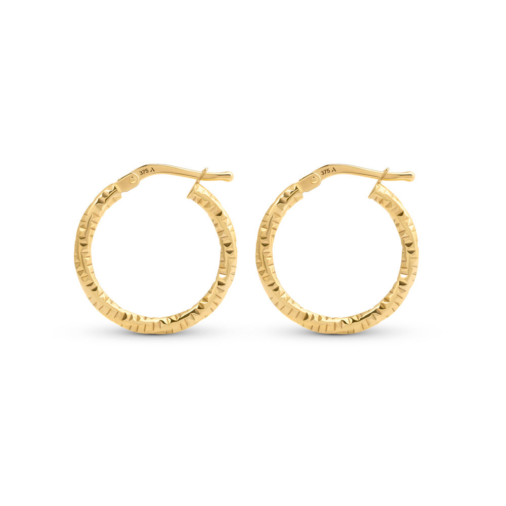 Gold hoop earrings with hammered pattern placed against a white background
