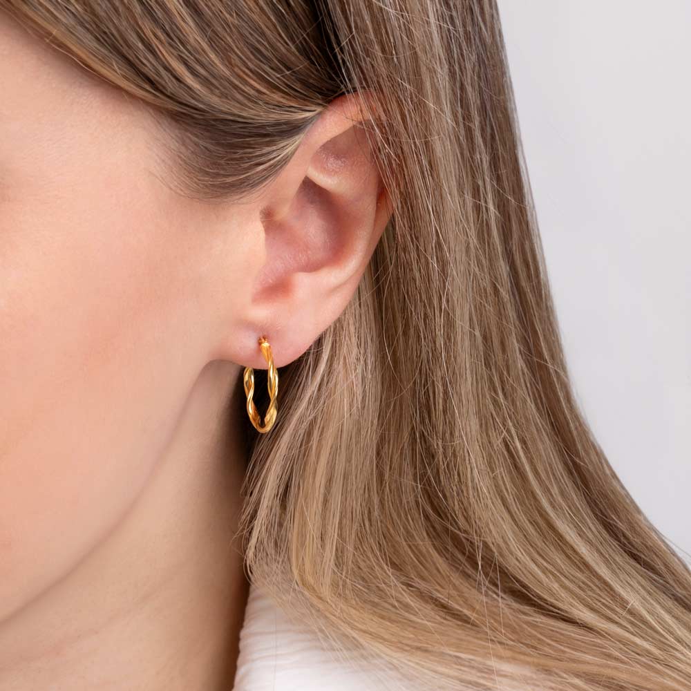 Close up picture of a woman wearing 9K double twisted hoop earrings
