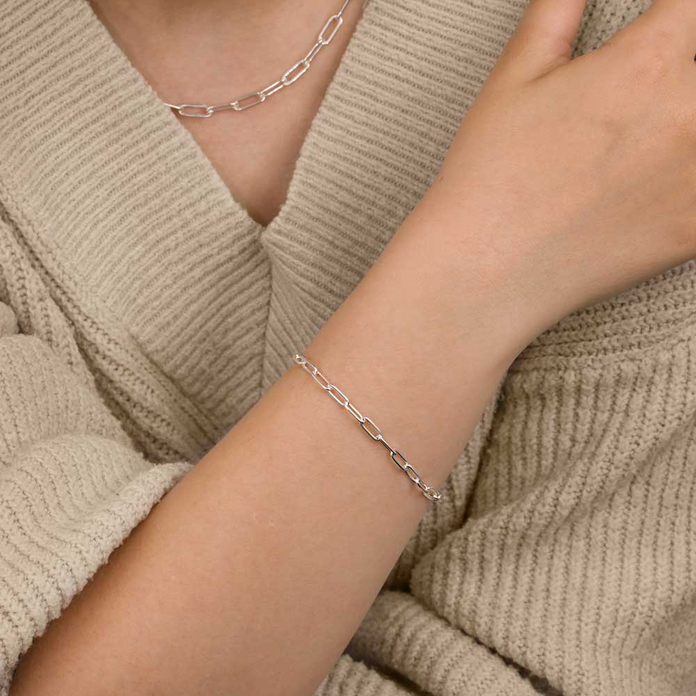 Close up of a woman's hand wearing paper clip bracelet with matching necklace
