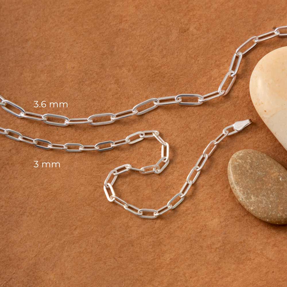 a pair of gold plated and silver paperclip bracelets placed on a brown surface