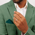 A man wearing a green suit and white shirt showing a 9ct white gold wedding band 2.5mm