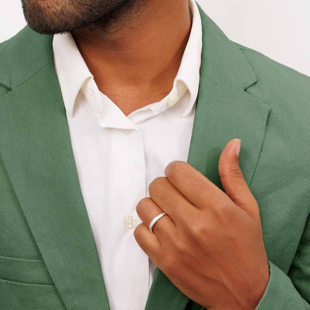 A man wearing a green suit and white shirt showing a 9ct white gold wedding band 3.5mm