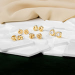 A picture of five different set of knot studs placed ona white marble
