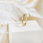 A 9ct gold wedding band with 1.3 mm cubic zirconia stone placed on a white and beige background