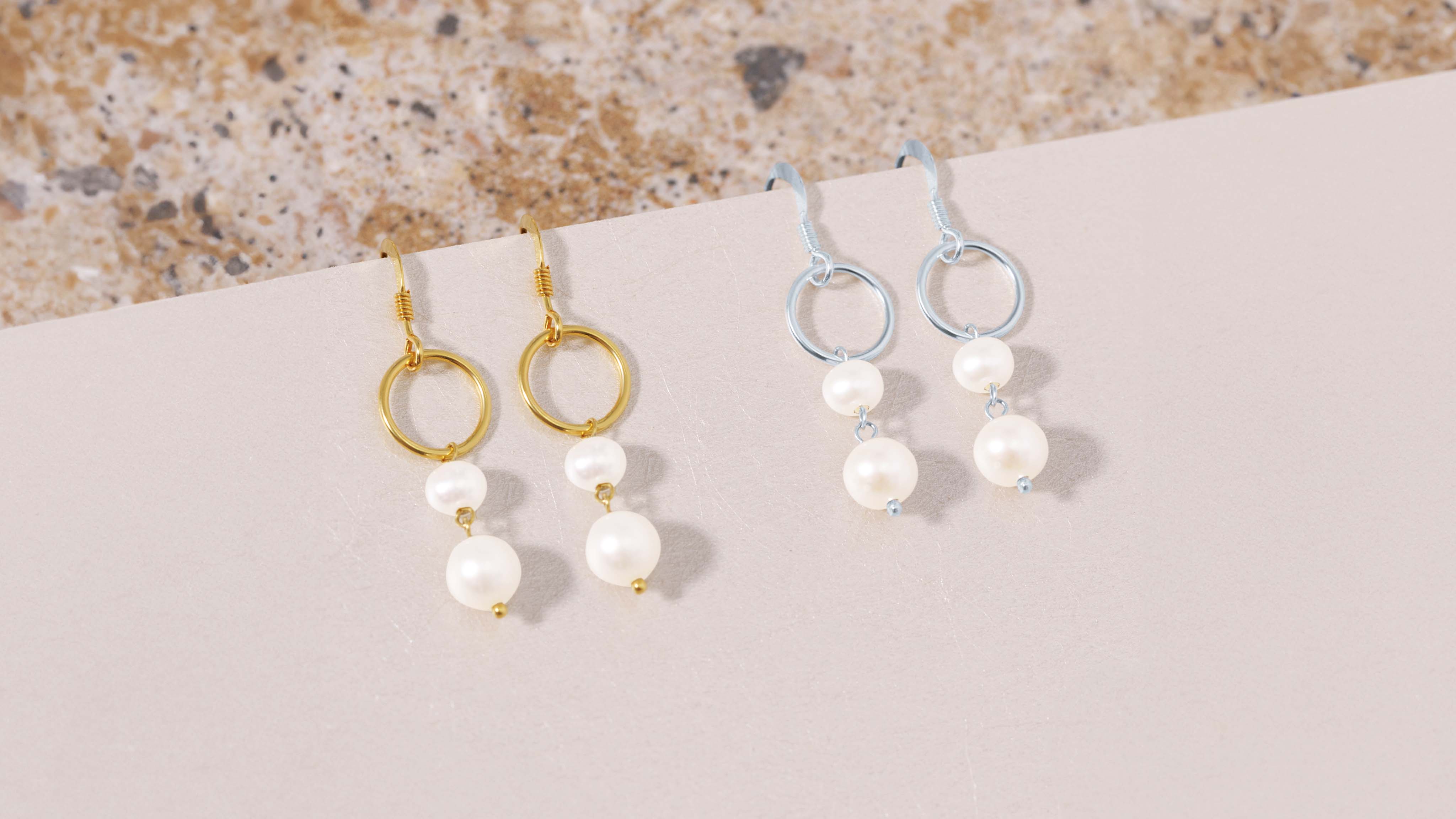 Gold-plated dangle earrings adorned with lustrous pearls, showcasing elegance and style.