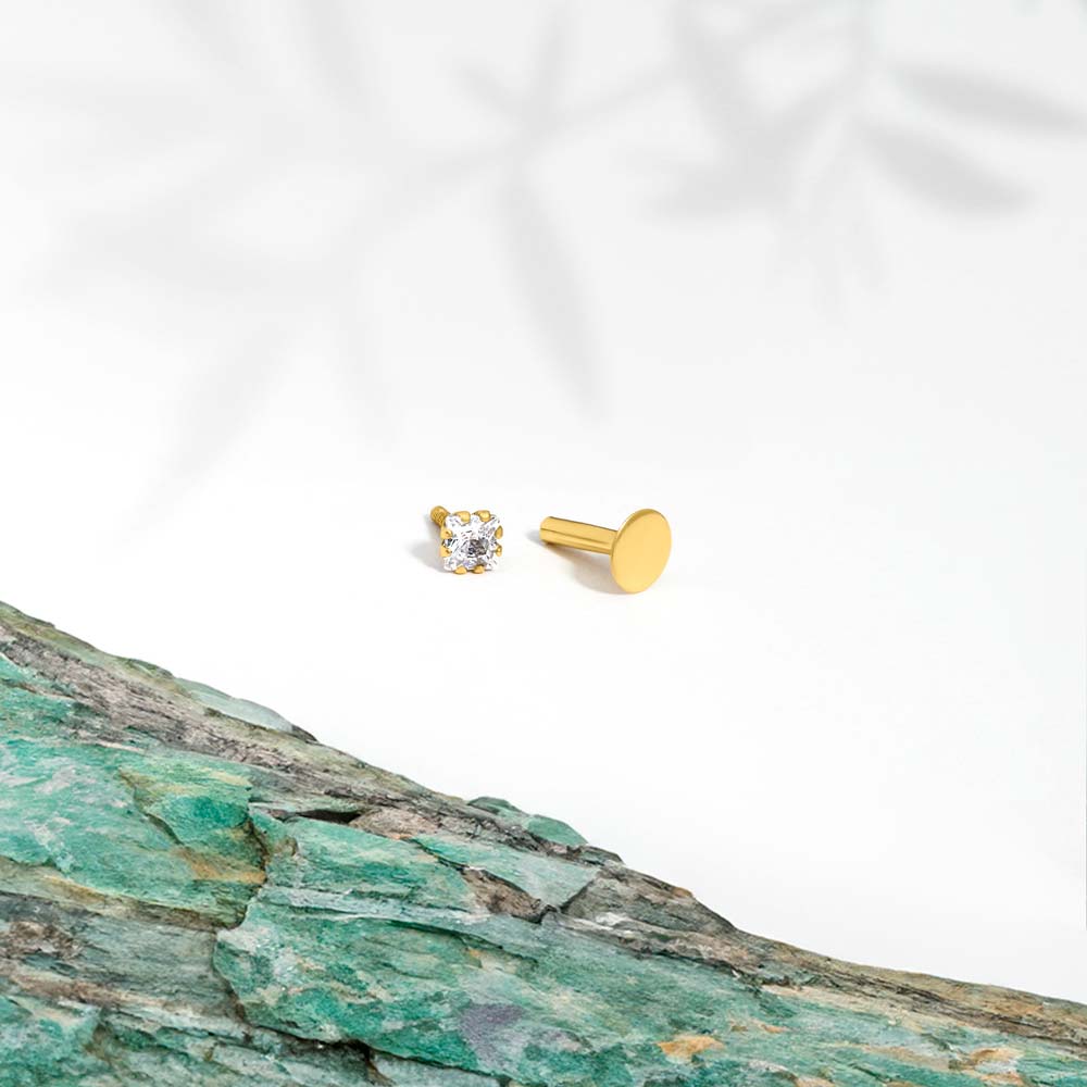 Marketing image 9ct gold piercing with one square shaped subic zirconia stone against white background and turquoise tile. 