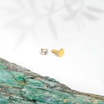 Marketing image 9ct gold piercing with one square shaped subic zirconia stone against white background and turquoise tile. 