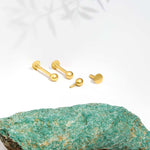 Marketing image 9ct gold 3mm ball piercing in 8mm length against white background and turquoise tile. 