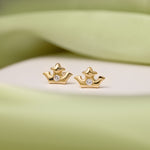 Pair of 9K gold crown studs presented on a white stone against green details.