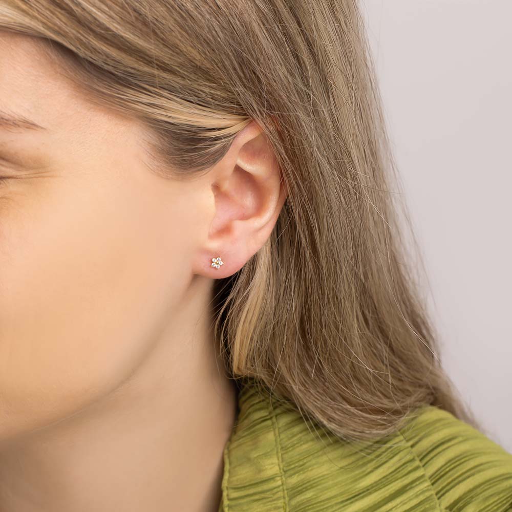 Close up of woman wearing 9K Gold Studs in Flower Design against white background.