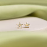 Pair of 9K gold flower studs presented on a white stone against green details.