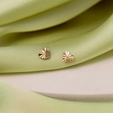 Pair of 9K gold heart studs presented on a white stone against green details.
