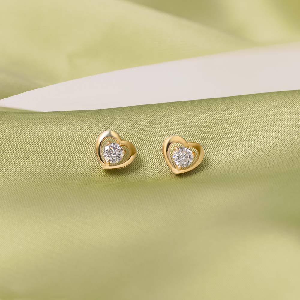 Pair of 9K gold heart studs presented on a white stone against green details.