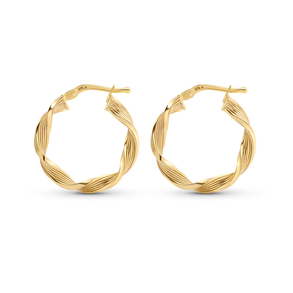 Gold hoop earrings with textured pattern placed against a white background