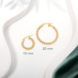 Two pairs of gold twisted hoops earrings placed on a white surface