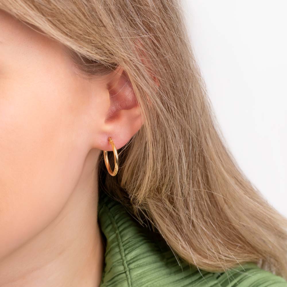 Close up picture of a woman wearing 9K twisted hoop earrings