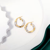 2 tone gold twisted hoops earrings placed on a white surface