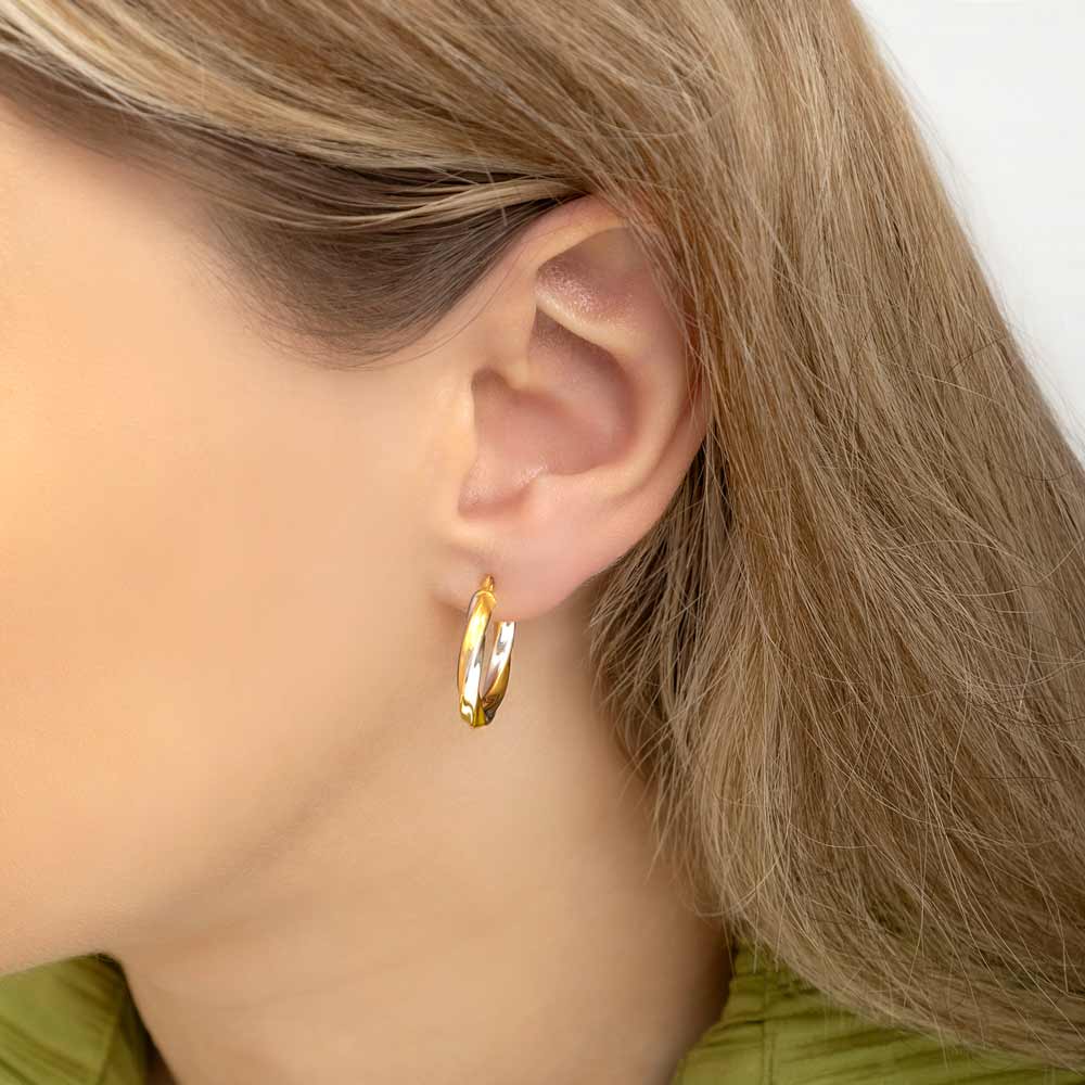 Close up picture of a woman wearing 2 tone 15 mm gold twisted hoop earrings