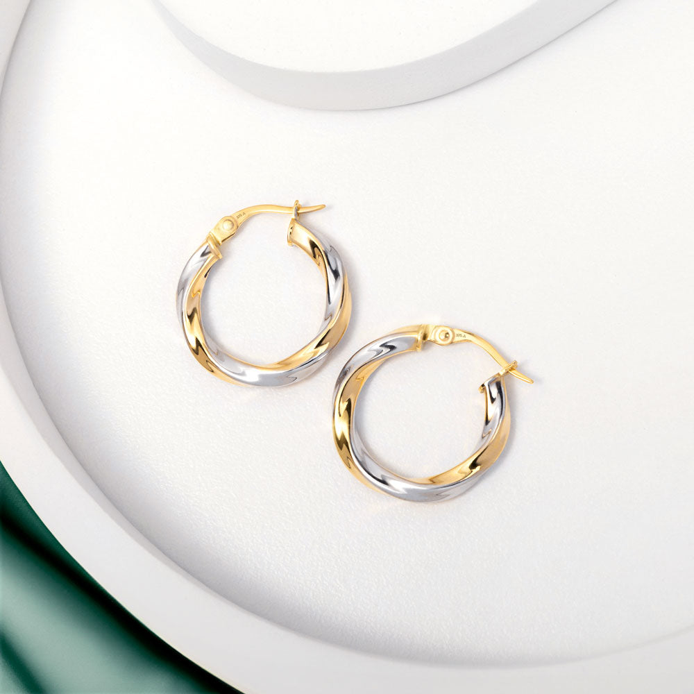 2 tone gold twisted hoops earrings placed on a white surface