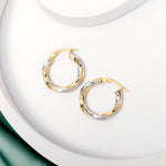 2 tone gold twisted hoops earrings placed on a white surface