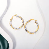 2 tone gold twisted hoops earrings placed on a white surface