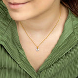 Woman wearing 9ct gold Round crystal pendant against green blouse. 