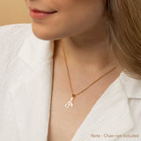 A woman wearing a gold necklace with an alphabet pendant in the shape of the letter 'A'. The text in the corner notes, "Note: Chain not included.