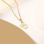 A delicate gold necklace is pictured with an alphabet pendant in the form of the letter 'C' resting on a cream-colored surface