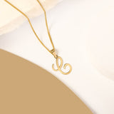 A delicate gold necklace is pictured with an alphabet pendant in the form of the letter 'C' resting on a cream-colored surface