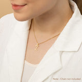 A woman wearing a gold necklace with an alphabet pendant in the shape of the letter 'I'. The text in the corner notes, "Note: Chain not included.