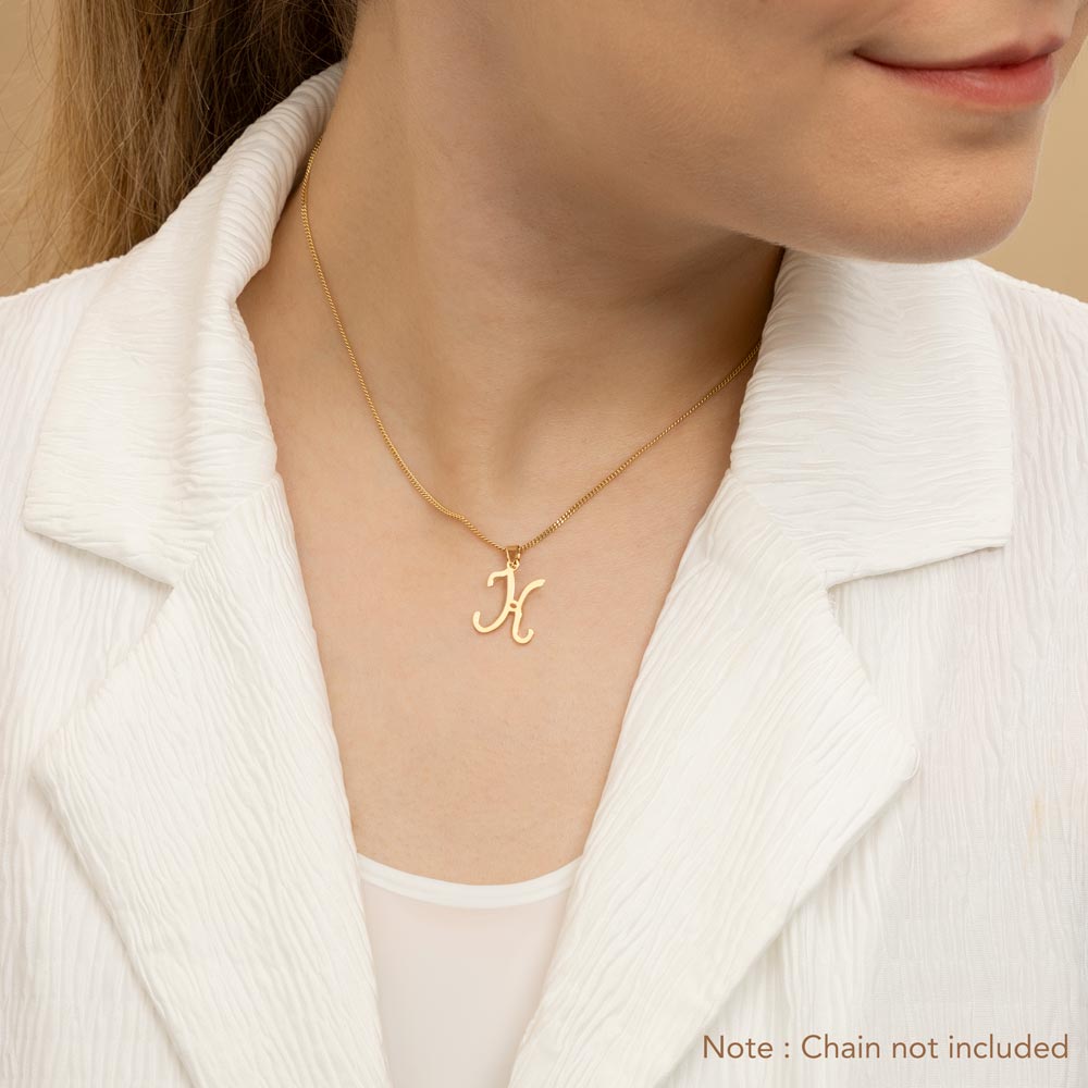 A woman wearing a gold necklace with an alphabet pendant in the shape of the letter 'K'. The text in the corner notes, "Note: Chain not included.