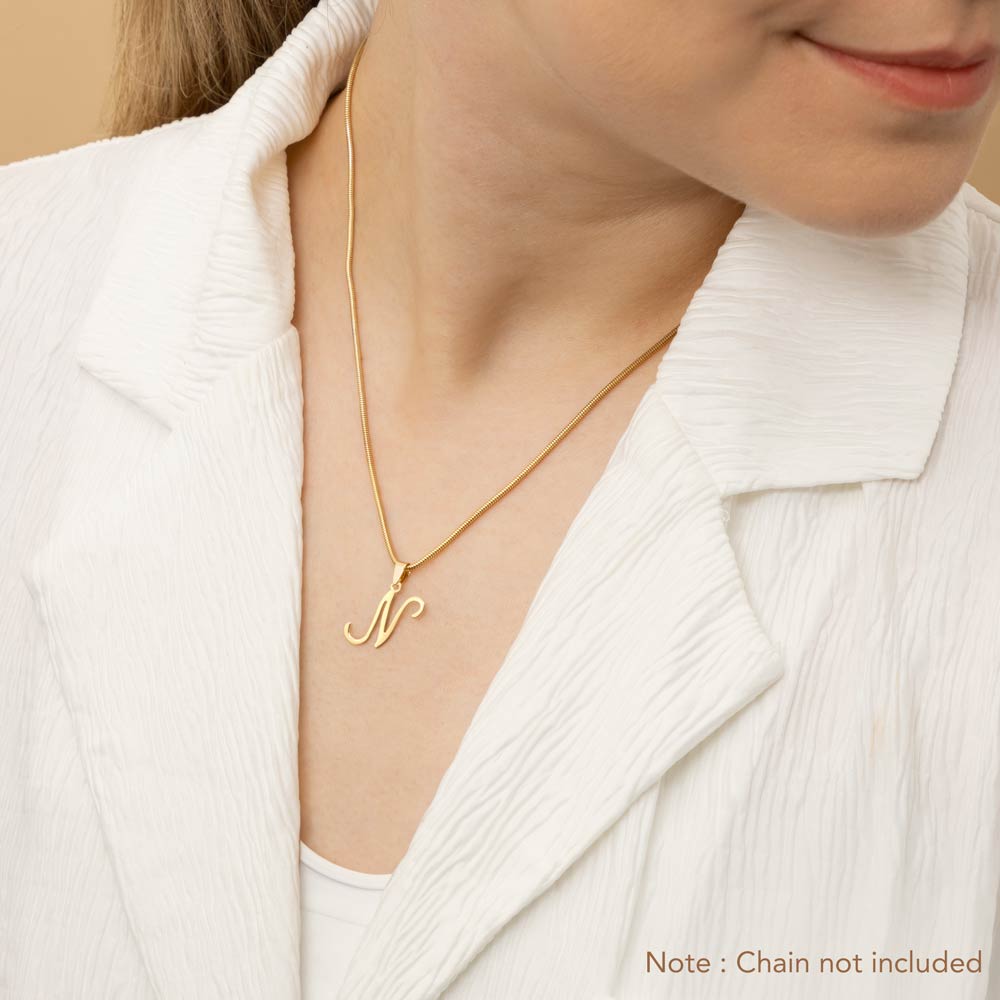 A woman wearing a gold necklace with an alphabet pendant in the shape of the letter 'N'. The text in the corner notes, "Note: Chain not included.