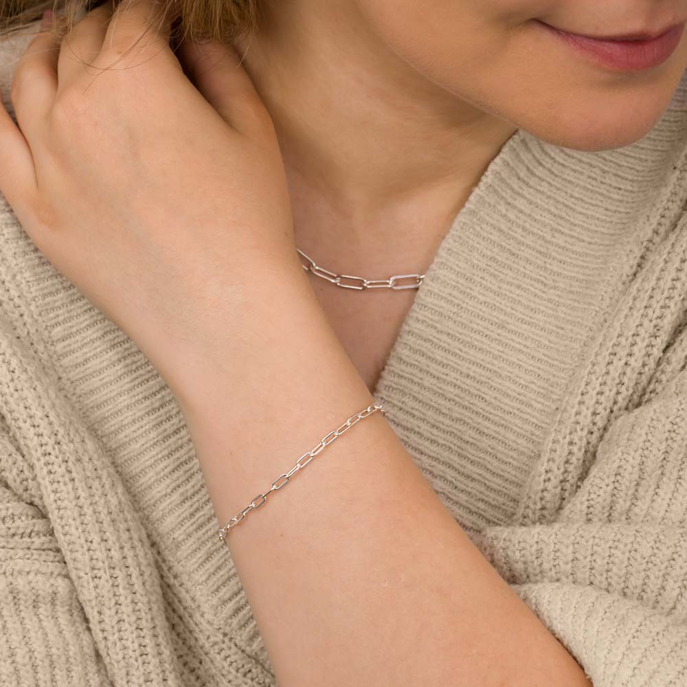 Close up of a woman's hand wearing paper clip bracelet with matching necklace