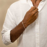 A man wearing a white shirt displaying the silver paperclip bracelet