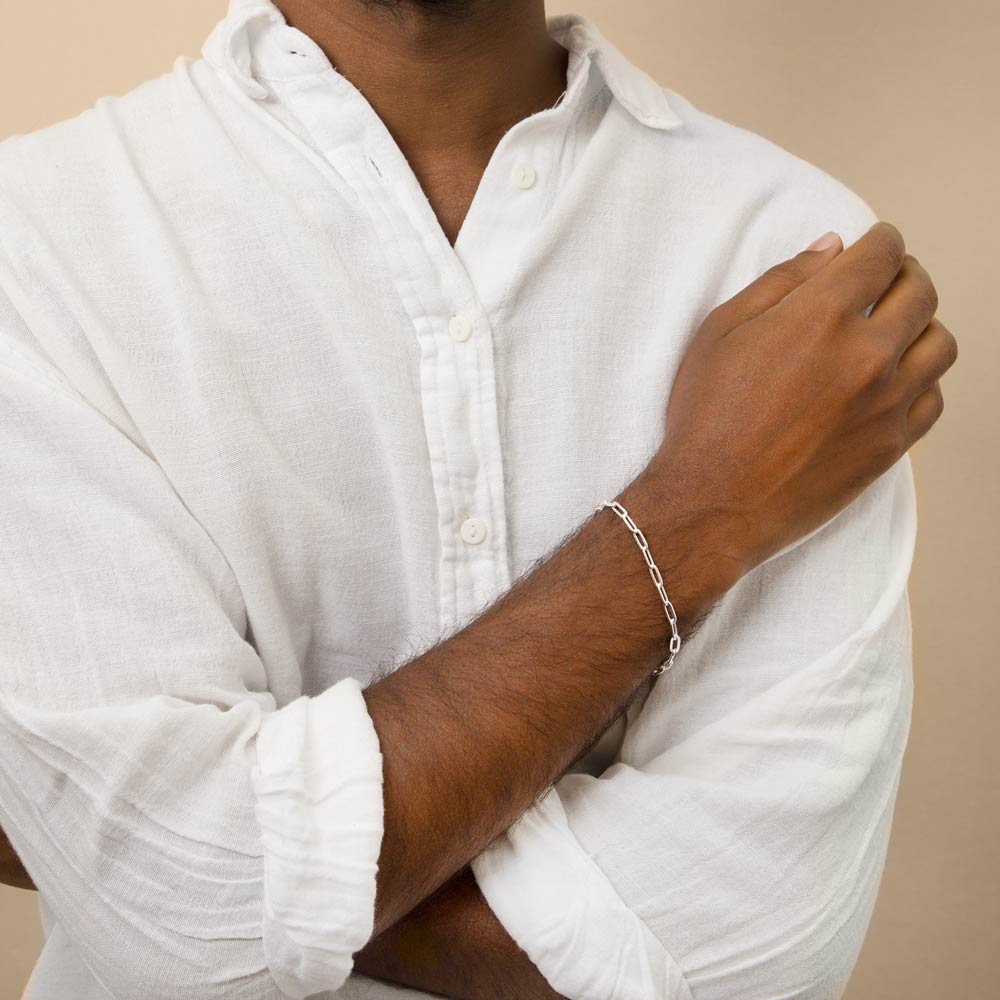 a man wearing a white shirt displaying the paperclip bracelet