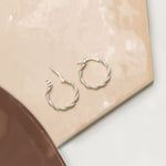 Marketing image of Silver Textured Hoops with post notch againts beige-brown tile.