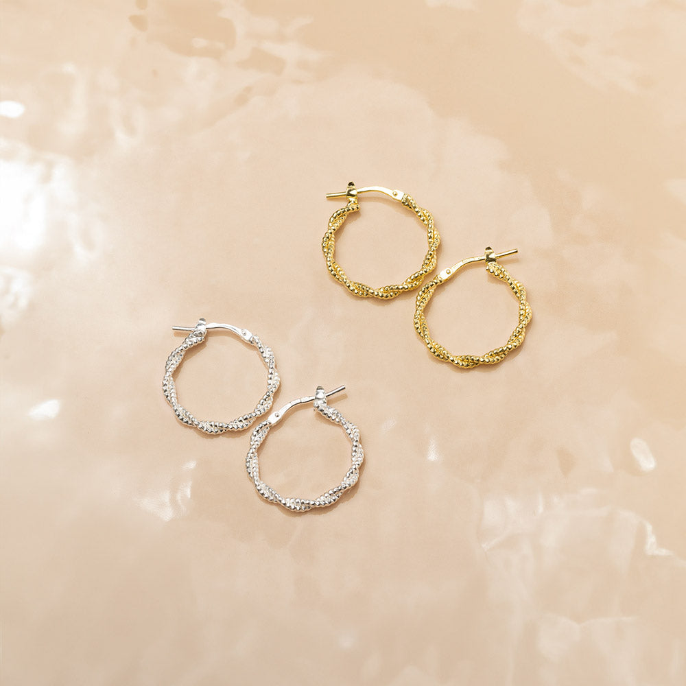 Marketing image of Silver and Gold plated Textured Hoops with post notch againts beige-brown tile.