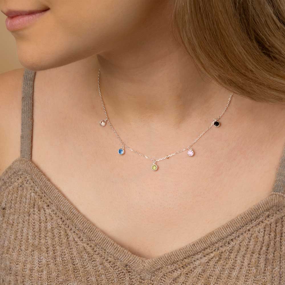 A woman wearing silver colourful round hanging charm pendant necklace around her neck in brown top