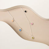 An image showing silver colourful round hanging charm pendant necklace placed on a beige and white background