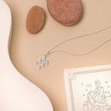 Flat lay of necklace with zodiac pendant on beige background and white details. 