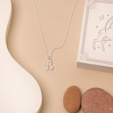 Flat lay of necklace with zodiac pendant on beige background and white details. 