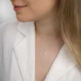 Woman wearing sagittarius zodiac necklace around her neck in white top.