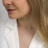 Woman wearing taurus zodiac necklace around her neck in white top.