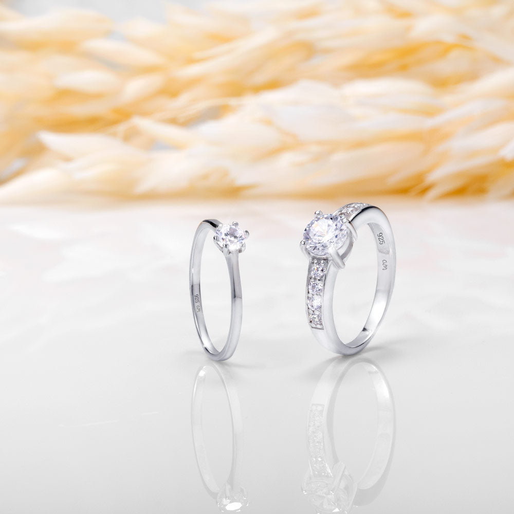 An image showing two silver engagement rings placed on a white and beige background.