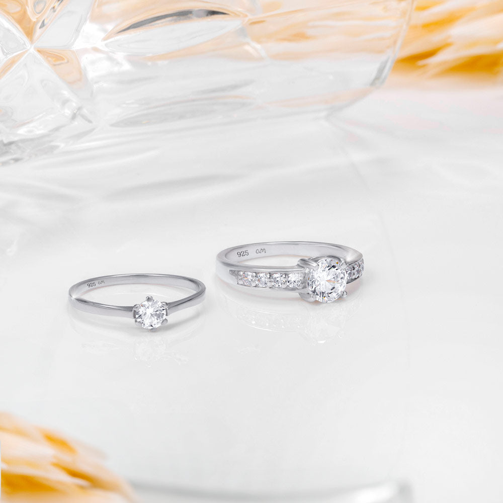 An image showing two silver engagement rings placed on a white and beige background.