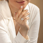 Woman wearing flat signet ring against white blouse. 