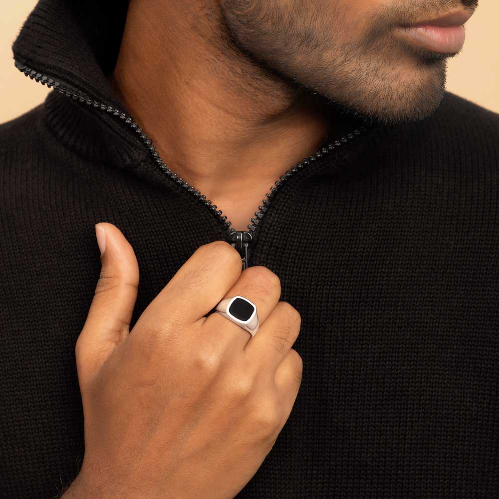 A man in a black sweater with a silve black onyx ring on his finger