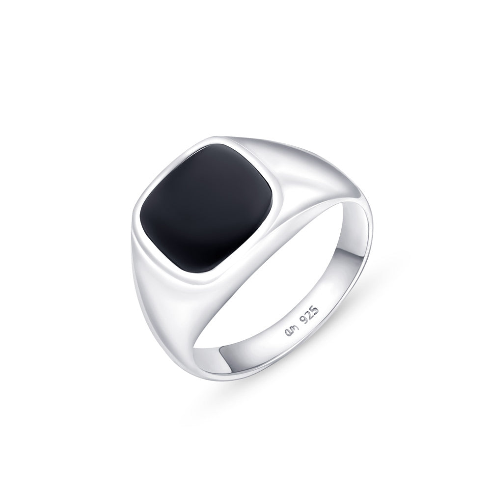 A silver signet ring with a flat black onyx stone agaionst a white background