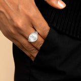 A man's hand wearing a silver ring symbolizing with St Christopher, the patron saint of travelers